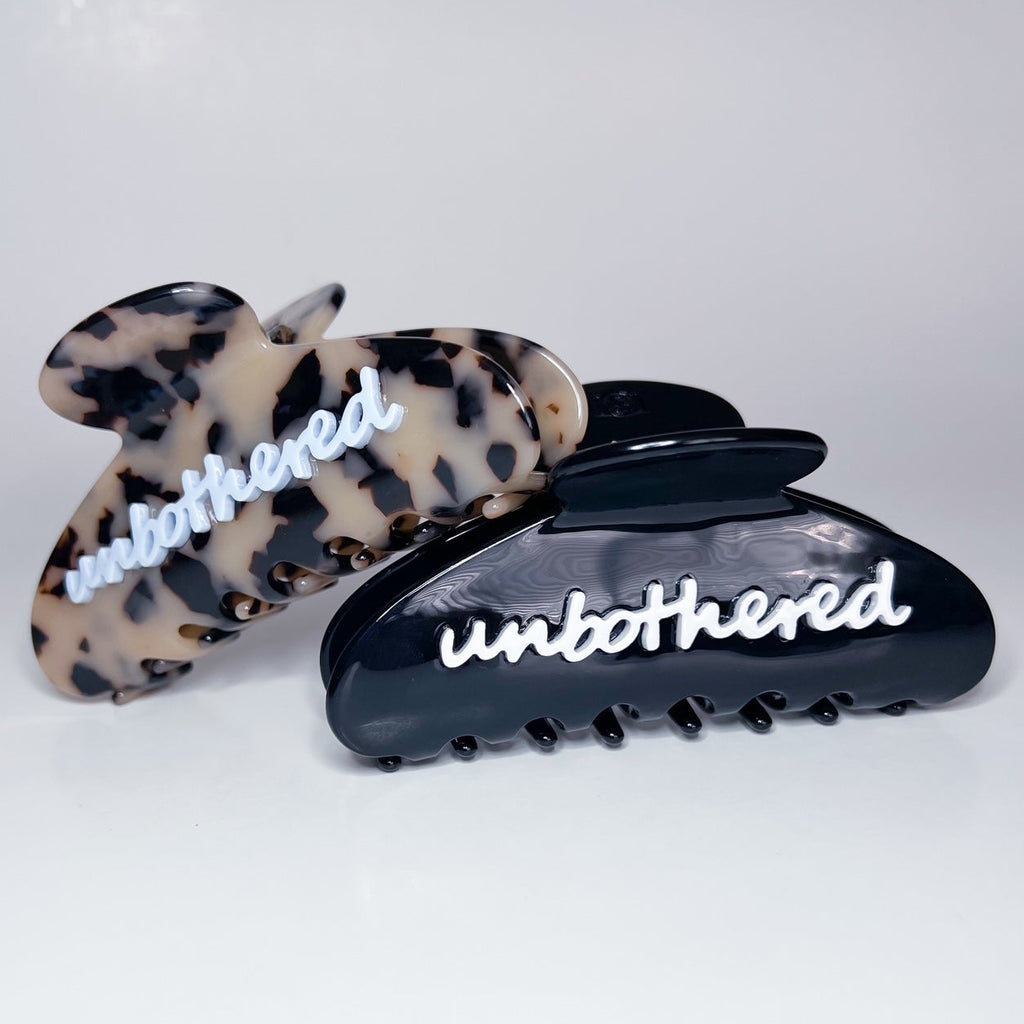 Two hair clips with 'unbothered' text on a white background